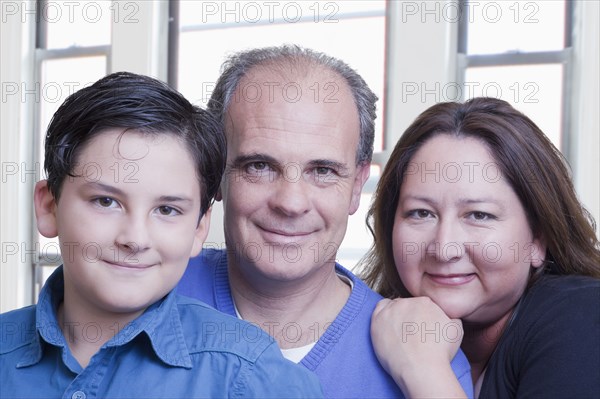 Hispanic father and wife posing with son