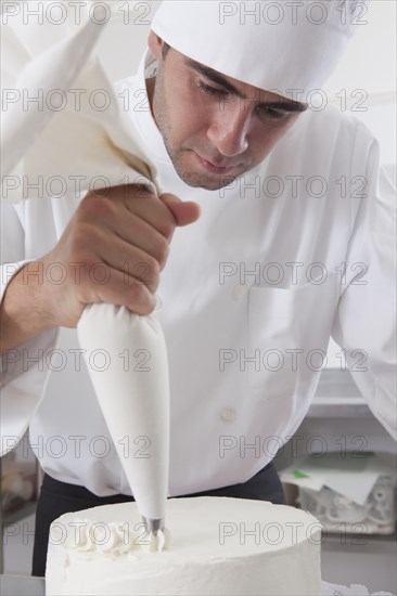 Hispanic chef decorating cake