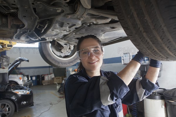 Smiling Hispanic mechanic repairing car