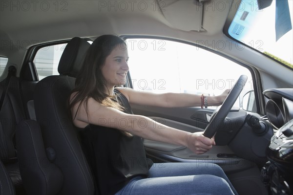 Smiling Hispanic woman driving car