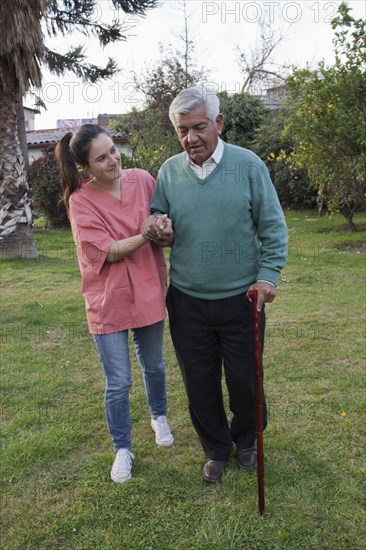 Hispanic nurse assisting man walking in grass