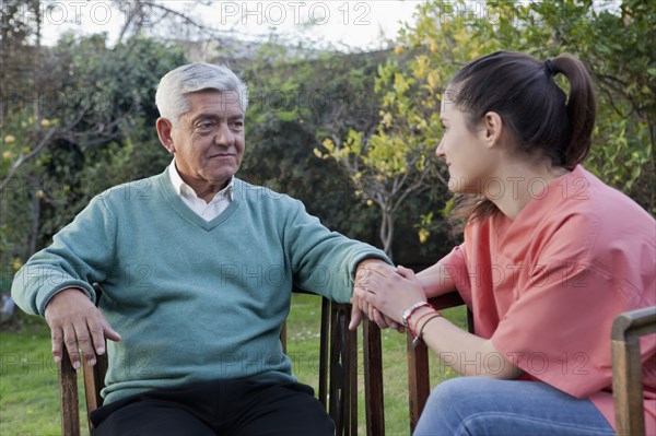 Hispanic nurse comforting man sitting in chair