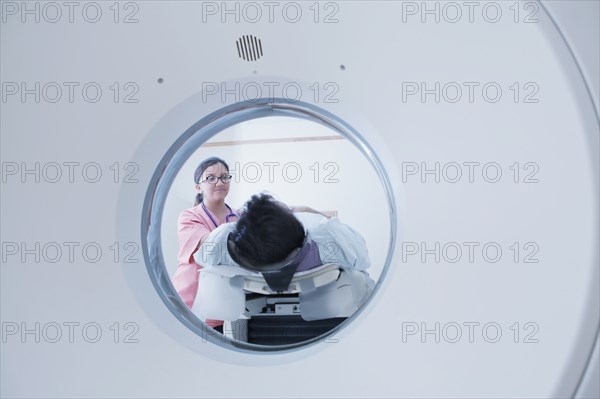 Hispanic nurse comforting patient at scanner