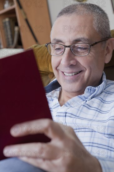 Smiling Hispanic man reading book