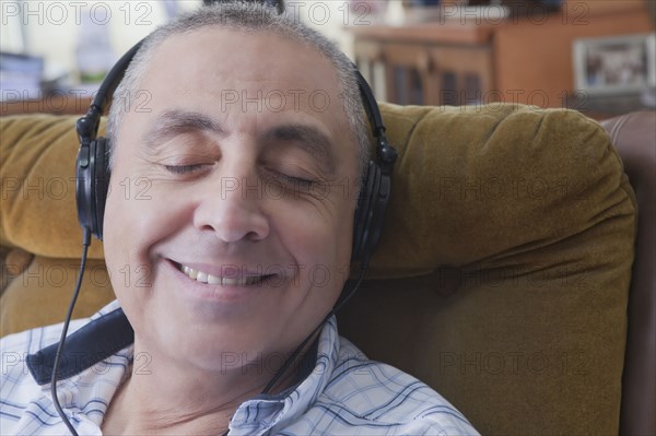 Smiling Hispanic man listening to headphones