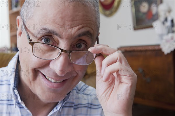 Smiling Hispanic man peering over eyeglasses