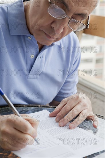 Hispanic man writing on paperwork