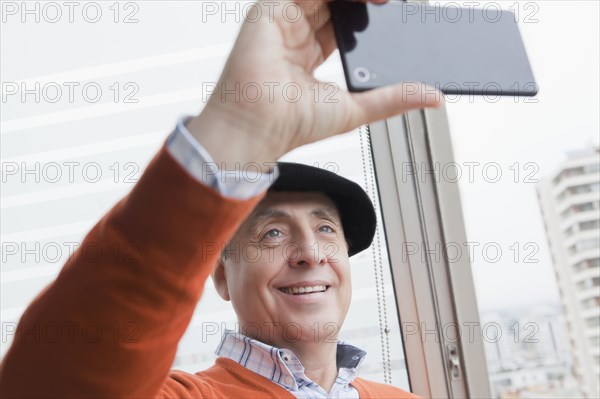 Smiling Hispanic man posing for cell phone selfie