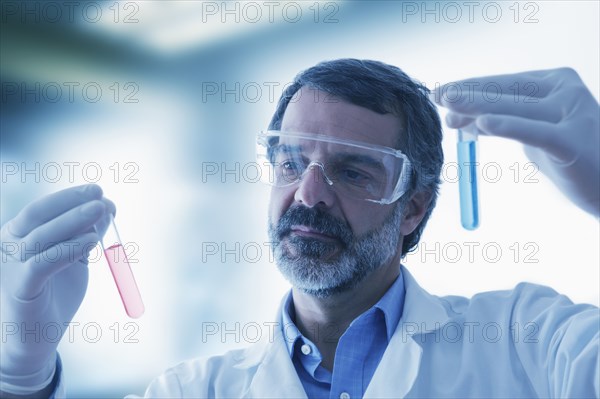 Hispanic researcher holding vials of red and blue liquid