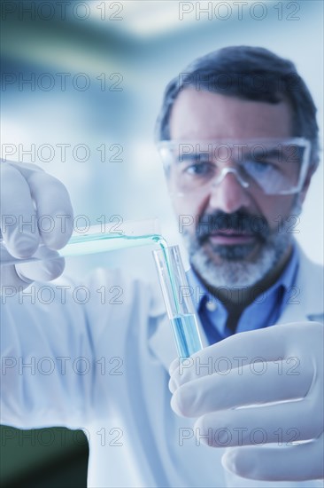 Hispanic researcher mixing vials of liquid