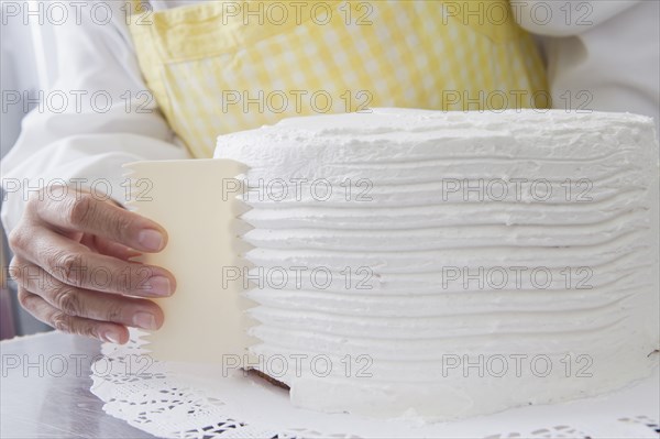 Hispanic woman shaping icing on cake