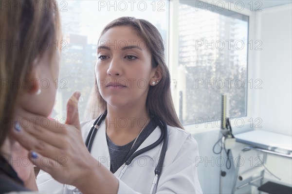 Hispanic doctor examining neck of patient