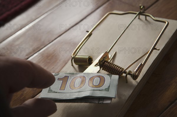 Hand of Hispanic man placing money in mousetrap