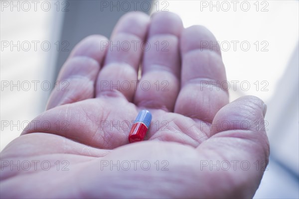 Hand of Hispanic man holding pill