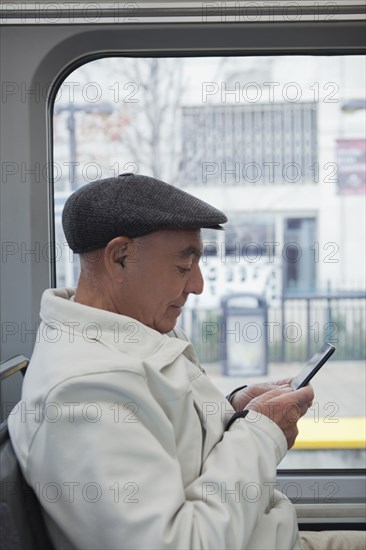 Hispanic man sitting on train texting on cell phone