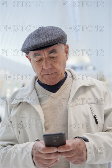 Serious Hispanic man texting on cell phone