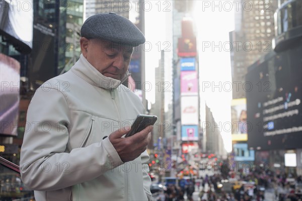 Hispanic man texting on cell phone in crowded city