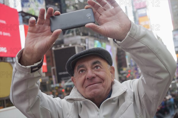 Hispanic man posing for cell phone selfie in city