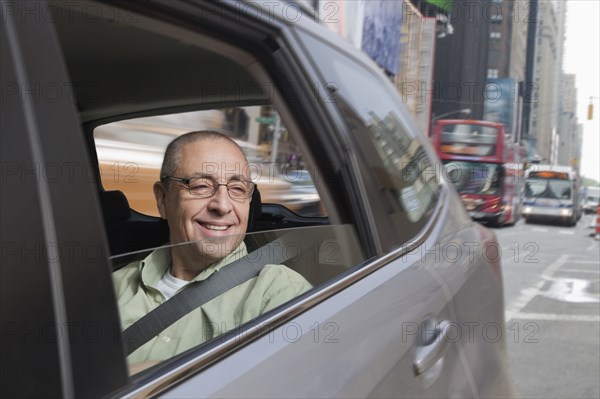 Smiling Hispanic man riding in car