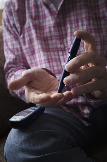 Diabetic Hispanic man checking blood in finger