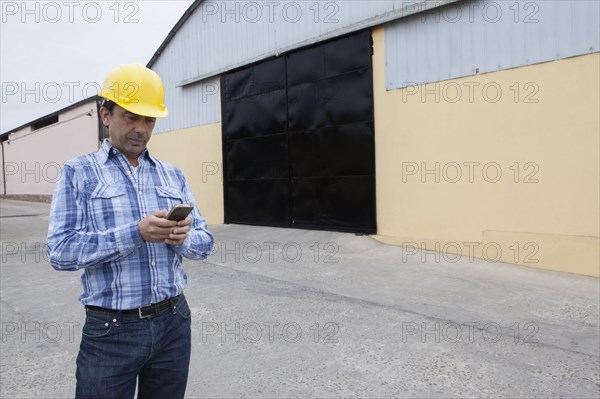 Mixed Race construction worker texting on cell phone