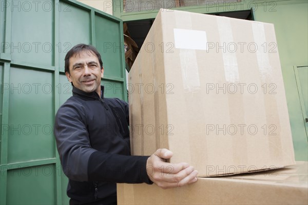 Mixed Race worker lifting cardboard box