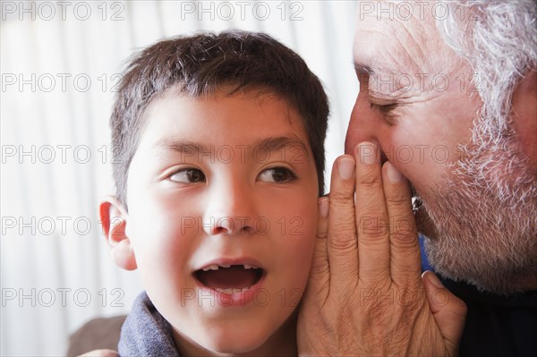 Hispanic grandfather whispering secret to grandson