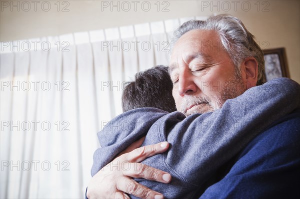 Hispanic grandfather hugging grandson