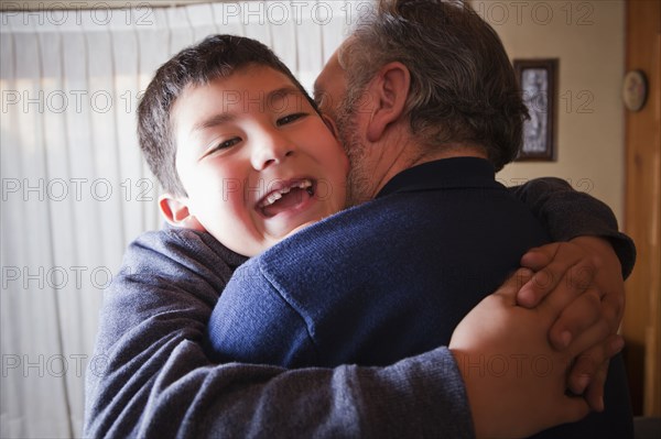 Hispanic grandfather hugging grandson