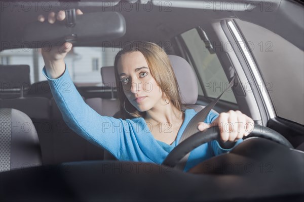 Hispanic woman adjusting rearview mirror