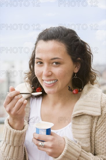 Hispanic woman eating yogurt