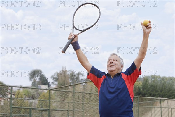 Excited senior Hispanic man playing tennis