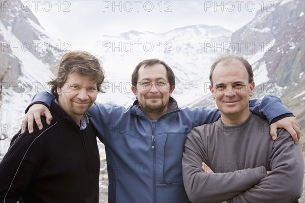 Hispanic friends hugging in snowy mountain valley