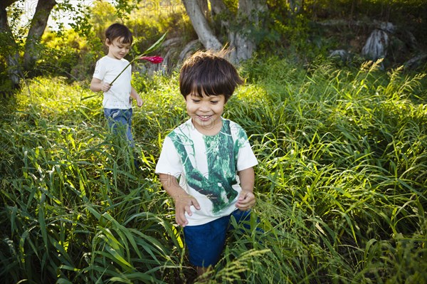 Mixed race children walking through tall grass