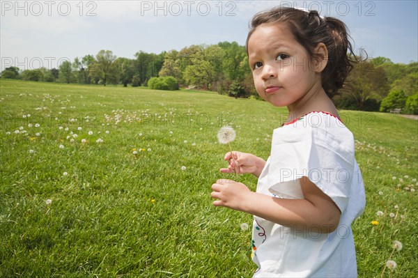 Girl walking in field with dandelion flower