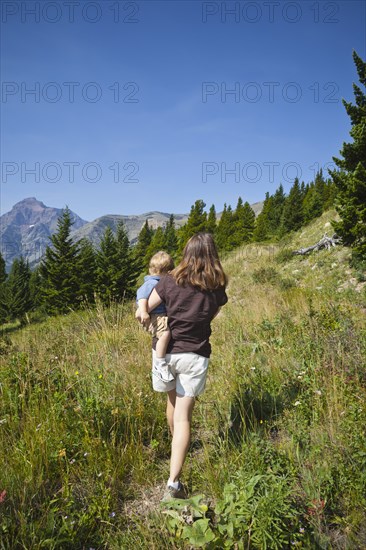 Mother carrying son on remote mountain path