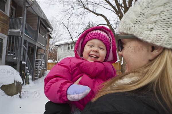 Mother holding grinning girl in coat