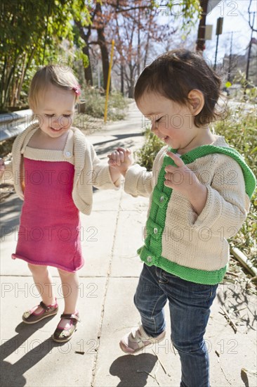 Caucasian girls holding hands on sidewalk