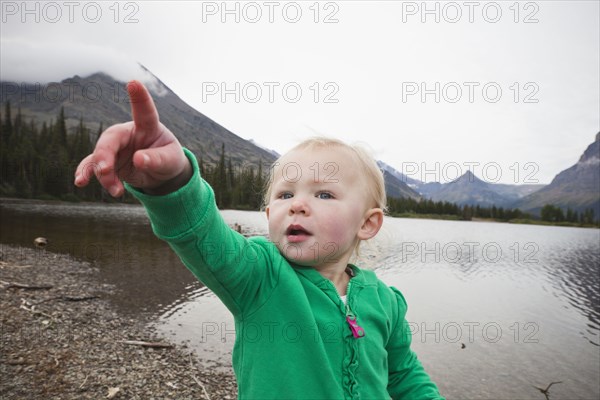Caucasian girl standing near lake pointing