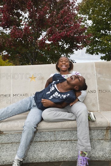 Laughing Black girls sitting on bench