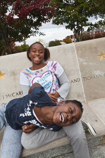 Laughing Black girls sitting on bench