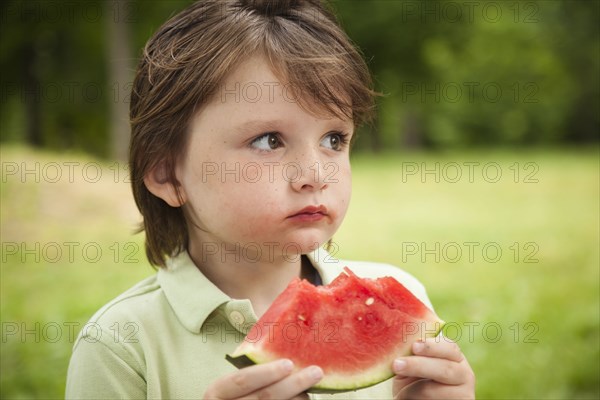 Caucasian boy eating watermelon outdoors