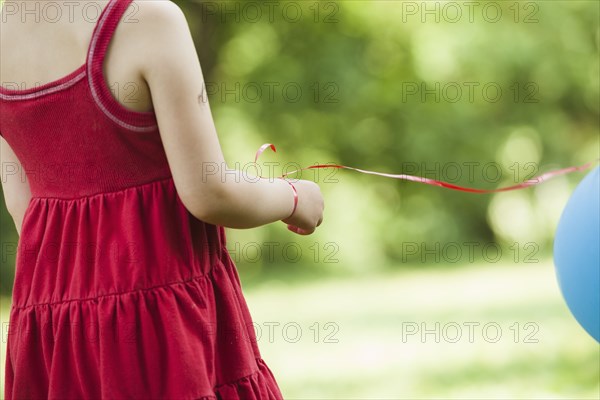 Girl with balloon tied to wrist outdoors