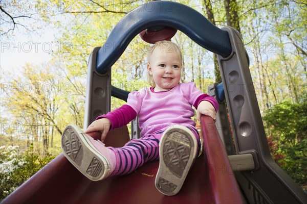 Caucasian girl playing on slide outdoors