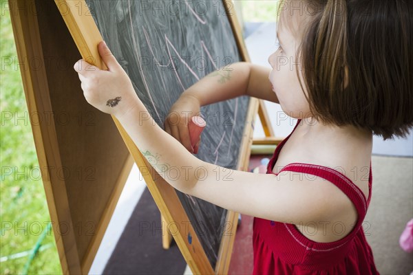 Girl drawing on blackboard easel