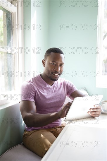 Black man using digital tablet at table
