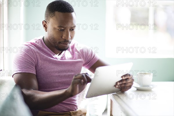 Black man using digital tablet at breakfast