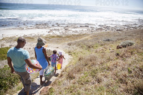 Mixed race family walking on path to beach