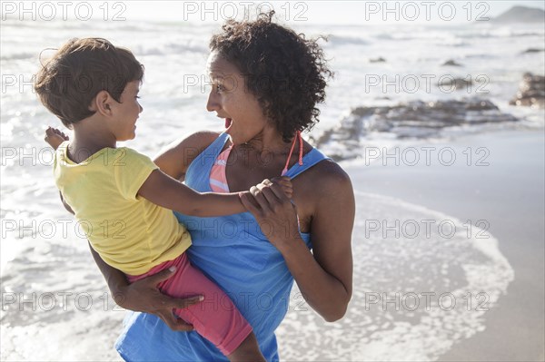 Mixed race mother and daughter playing on beach