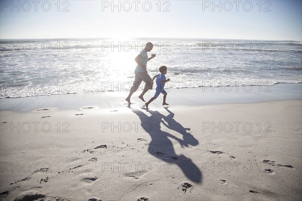 Mixed race father and son running on beach